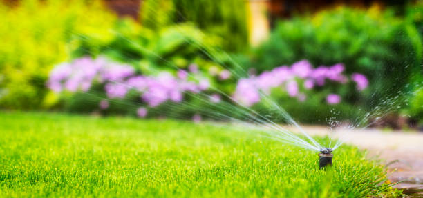 A smart irrigation system efficiently watering a lush green garden with vibrant flowers in the background.