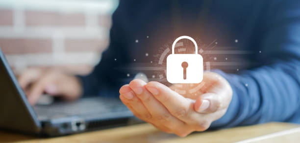 Person holding a virtual padlock symbol in front of a laptop, representing data protection in consumer electronics.